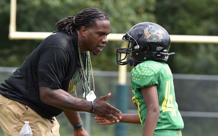 Featured: Coach Kiven with a young member of the Montgomery Village Chief athletes. The full time volunteer job requires coaching, mentoring, educating and emotional support.